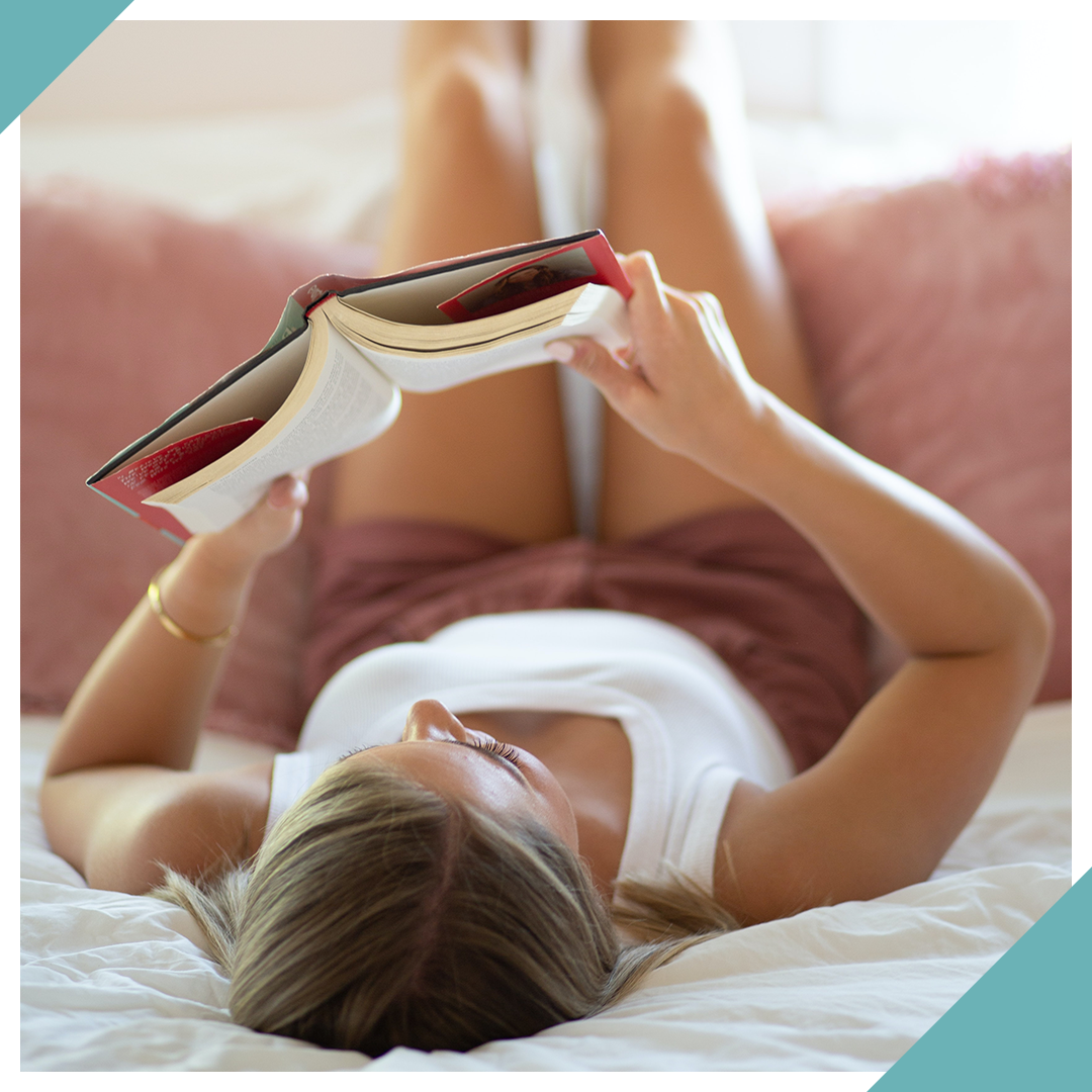 woman laying on bed reading a book